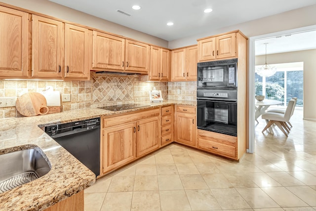 kitchen featuring light stone counters, backsplash, black appliances, and light brown cabinetry