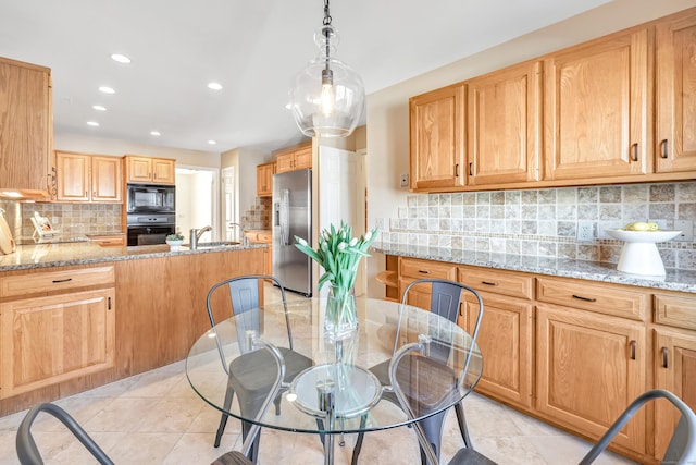 kitchen with decorative light fixtures, sink, backsplash, light stone counters, and black appliances