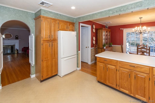 kitchen with hanging light fixtures, crown molding, a chandelier, and white fridge