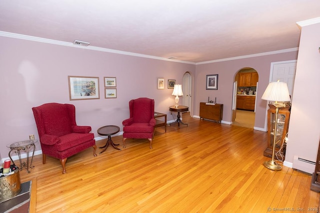 living area featuring ornamental molding, baseboard heating, and light hardwood / wood-style floors