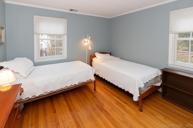 bedroom featuring ornamental molding and light hardwood / wood-style flooring