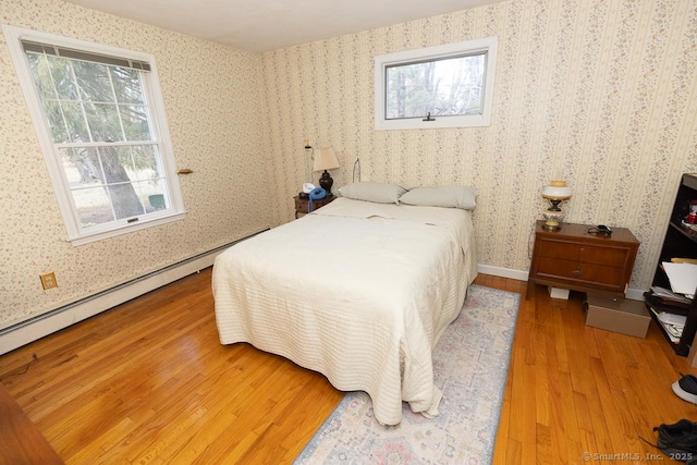 bedroom featuring wood-type flooring and a baseboard heating unit