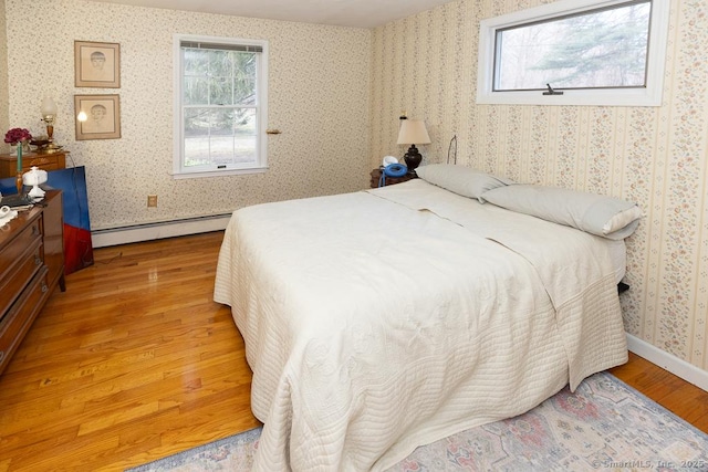 bedroom with light hardwood / wood-style flooring and baseboard heating