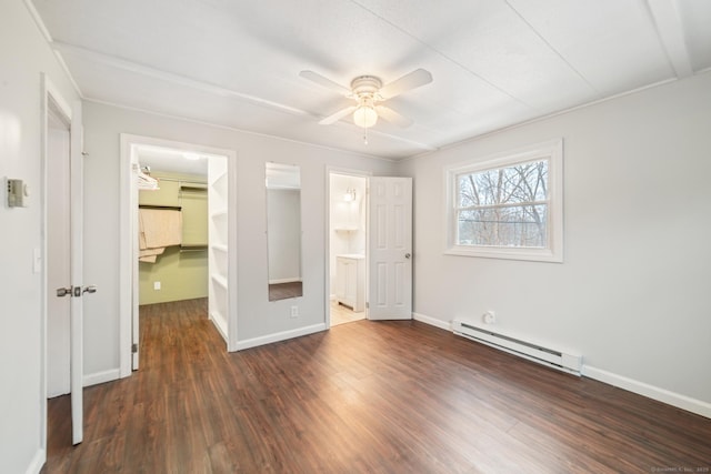 unfurnished bedroom with a baseboard radiator, dark hardwood / wood-style flooring, a walk in closet, ceiling fan, and a closet