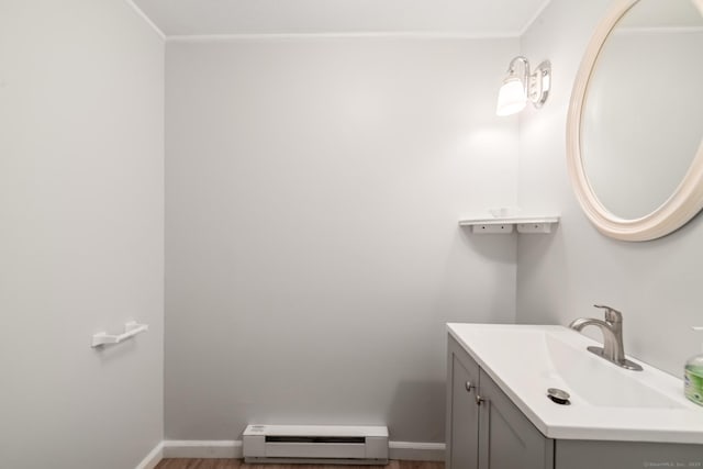 bathroom with ornamental molding, vanity, wood-type flooring, and a baseboard heating unit