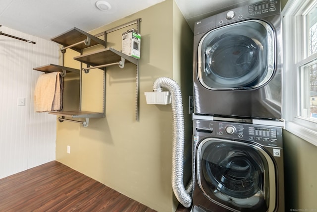 laundry area with stacked washer and dryer and dark wood-type flooring