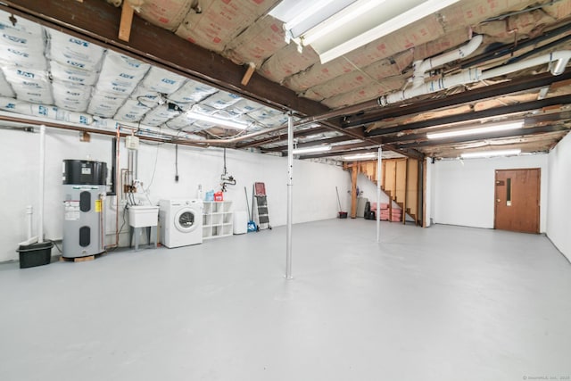 basement featuring sink, washer and clothes dryer, and hybrid water heater