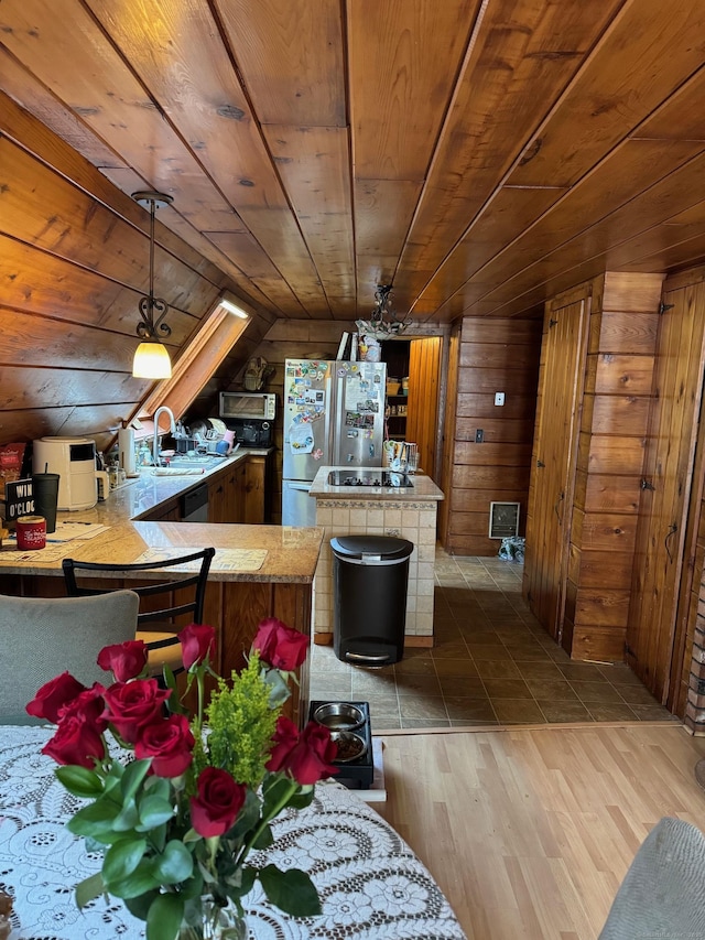 kitchen featuring wooden walls, appliances with stainless steel finishes, kitchen peninsula, and wooden ceiling