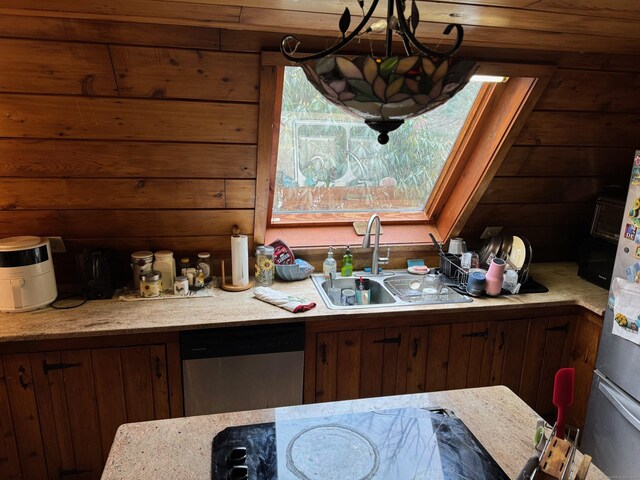 kitchen featuring wood walls, sink, and dishwasher