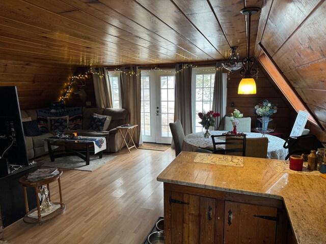 interior space with light wood-type flooring, vaulted ceiling, wood ceiling, and wood walls