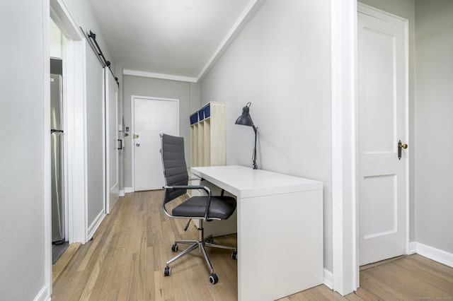 office area with light hardwood / wood-style floors and a barn door