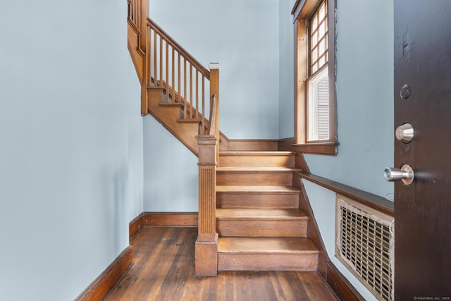 staircase featuring baseboards, visible vents, and wood finished floors