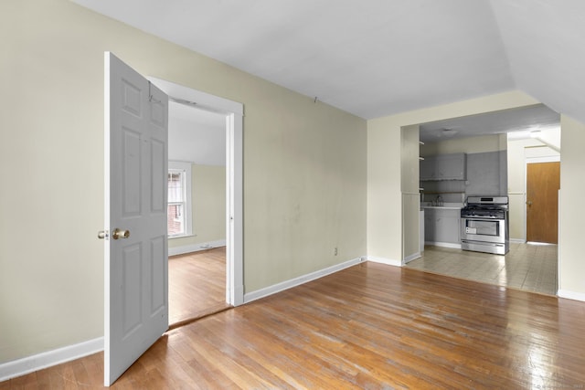 unfurnished living room featuring a sink, light wood-style flooring, and baseboards