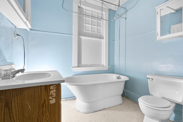 full bathroom featuring toilet, tile patterned flooring, a freestanding bath, and vanity