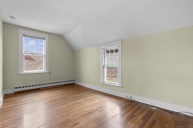 additional living space with a baseboard heating unit, light wood-type flooring, and vaulted ceiling