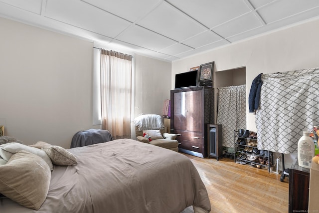 bedroom with wood finished floors and a paneled ceiling