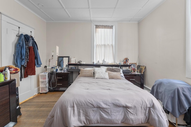 bedroom with a baseboard heating unit, crown molding, and dark wood finished floors