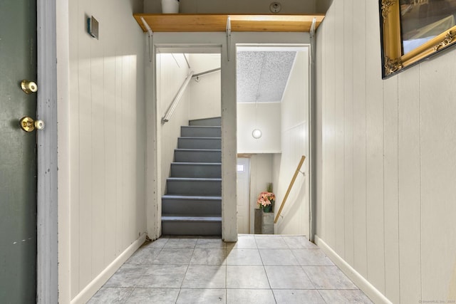 staircase featuring wooden walls and tile patterned floors