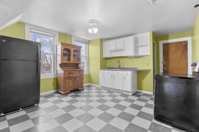 kitchen with white cabinets, freestanding refrigerator, light floors, open shelves, and a sink