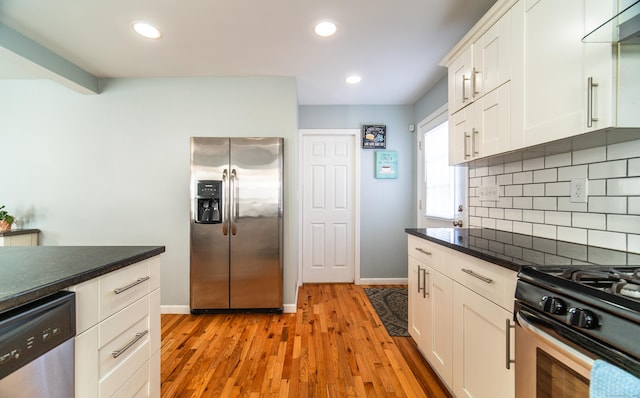 kitchen featuring light hardwood / wood-style flooring, appliances with stainless steel finishes, white cabinets, range hood, and backsplash