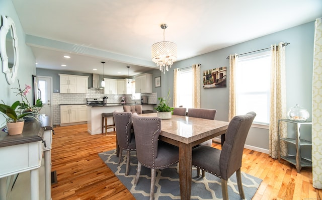 dining area featuring a healthy amount of sunlight, a notable chandelier, and light hardwood / wood-style flooring