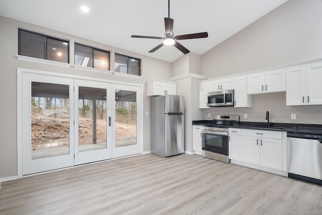 kitchen with white cabinetry, dark countertops, appliances with stainless steel finishes, and a sink