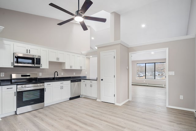 kitchen with dark countertops, ceiling fan, appliances with stainless steel finishes, white cabinetry, and a baseboard radiator