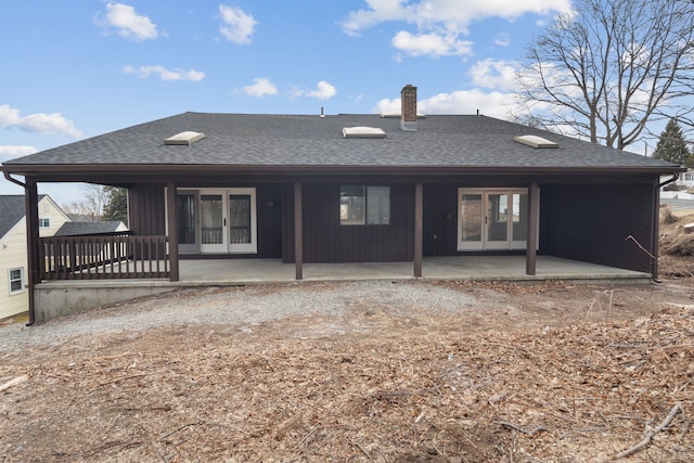 rear view of house featuring french doors, roof with shingles, a chimney, and a patio area