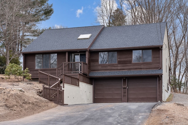 chalet / cabin featuring driveway, an attached garage, stairs, and a shingled roof