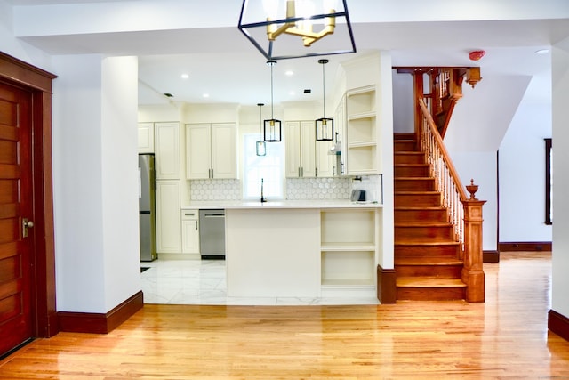 kitchen with sink, hanging light fixtures, light wood-type flooring, stainless steel appliances, and decorative backsplash