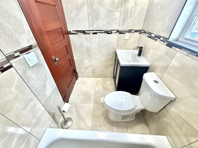 bathroom with vanity, a tub to relax in, tile walls, and toilet