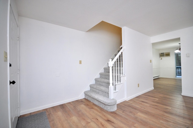 stairs featuring hardwood / wood-style floors, a baseboard radiator, and an AC wall unit