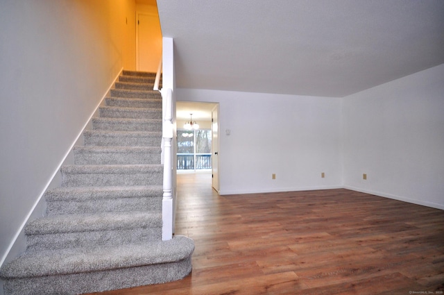 stairway featuring wood-type flooring and a chandelier