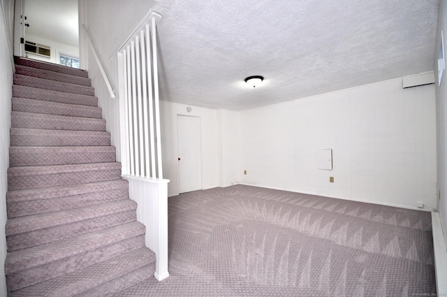 staircase featuring carpet floors and a textured ceiling