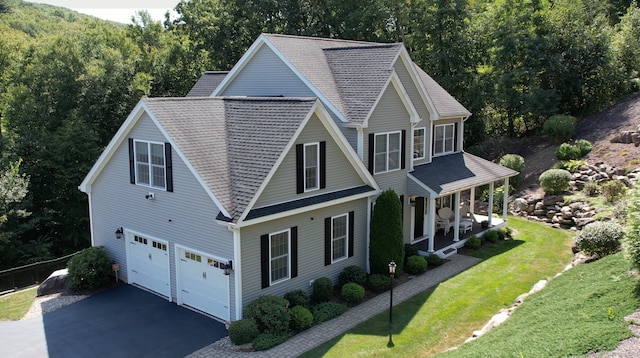 view of home's exterior featuring a porch, a garage, and a lawn