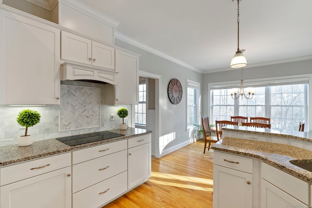 kitchen featuring black electric stovetop, decorative light fixtures, custom exhaust hood, and white cabinets