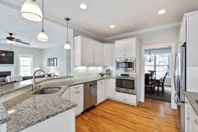 kitchen featuring sink, white cabinets, hanging light fixtures, kitchen peninsula, and stainless steel appliances