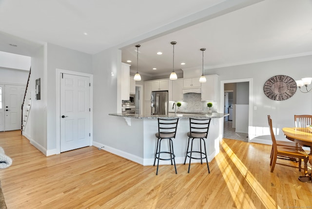 kitchen featuring stainless steel refrigerator with ice dispenser, stone countertops, hanging light fixtures, kitchen peninsula, and white cabinets