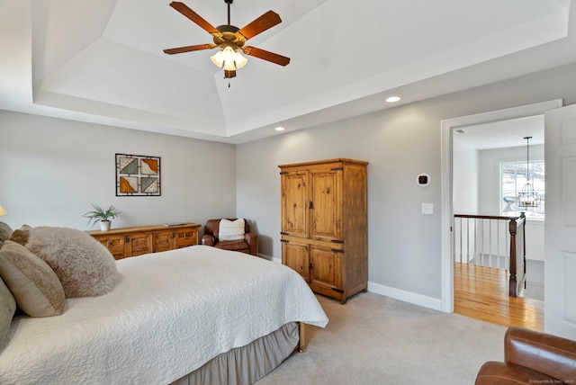 carpeted bedroom with a tray ceiling, ceiling fan with notable chandelier, and vaulted ceiling