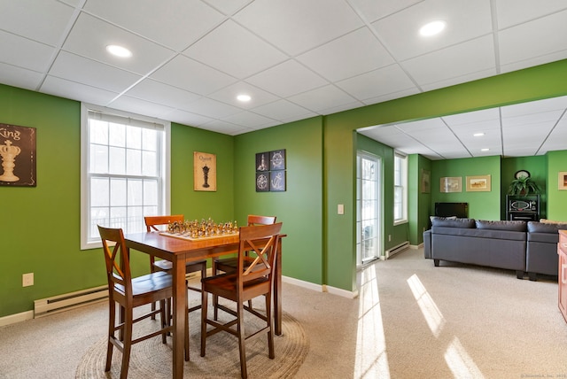 dining area with a baseboard radiator, a paneled ceiling, and light carpet