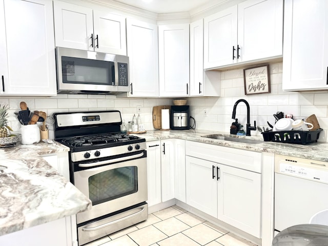 kitchen with tasteful backsplash, sink, white cabinets, and appliances with stainless steel finishes