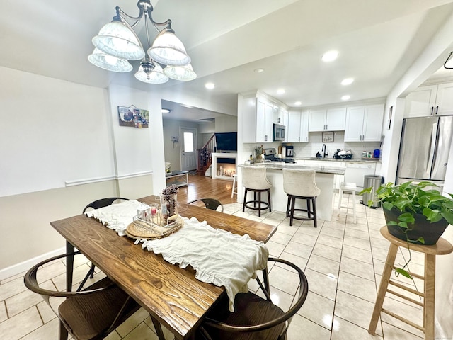 dining area with light tile patterned flooring, sink, and an inviting chandelier