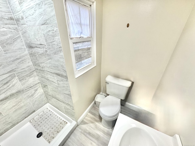 bathroom featuring a tile shower, hardwood / wood-style flooring, and toilet