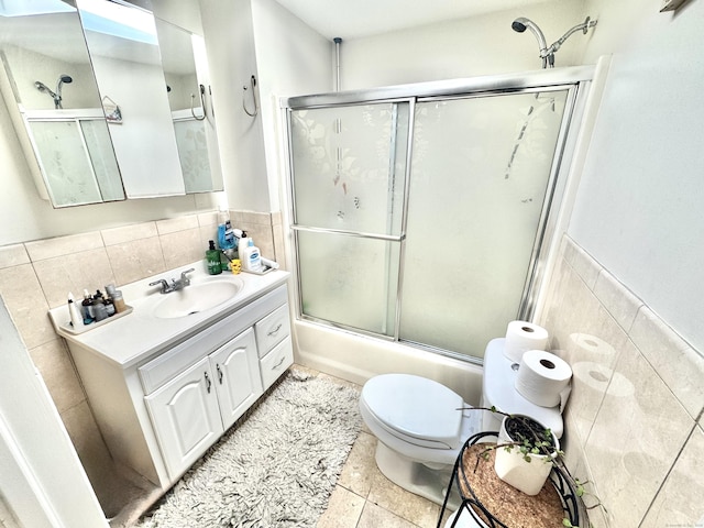 full bathroom with tile patterned floors, toilet, combined bath / shower with glass door, tile walls, and vanity