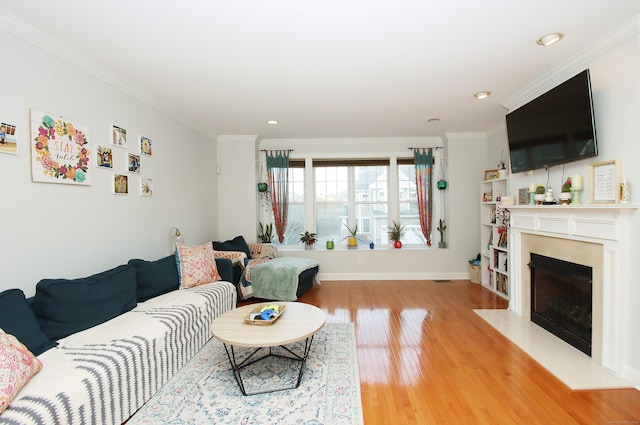 living room featuring a fireplace, wood-type flooring, and ornamental molding