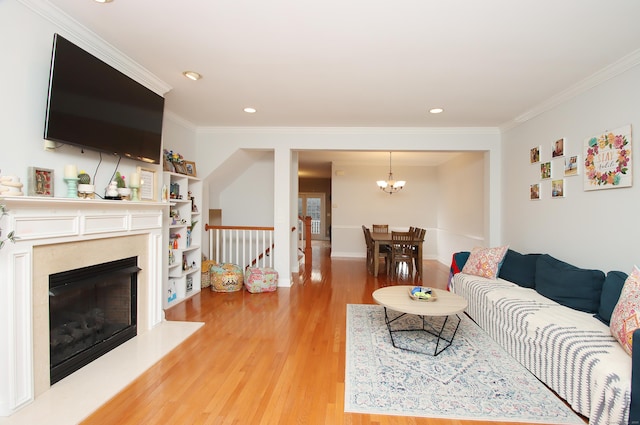 living room with hardwood / wood-style flooring, crown molding, a premium fireplace, and a notable chandelier