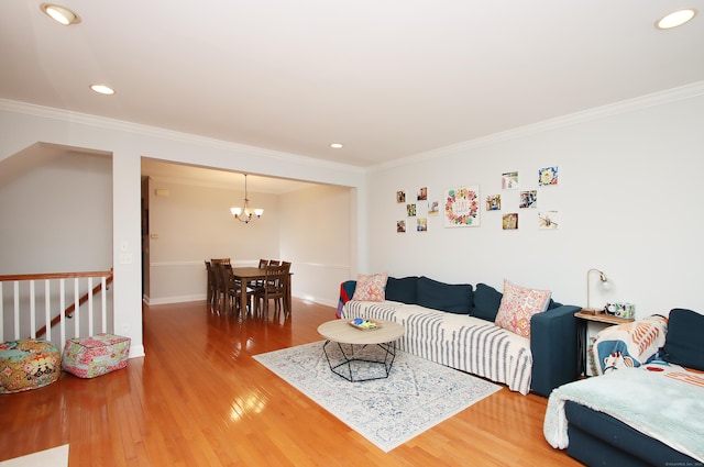 living room with wood-type flooring, ornamental molding, and a chandelier