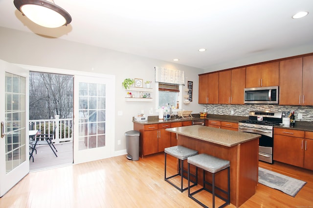 kitchen featuring stainless steel appliances, a kitchen breakfast bar, a kitchen island, decorative backsplash, and light wood-type flooring