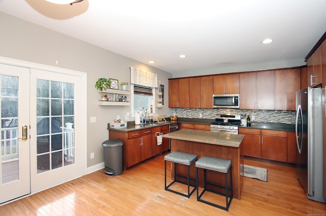 kitchen featuring appliances with stainless steel finishes, tasteful backsplash, sink, a center island, and light hardwood / wood-style flooring