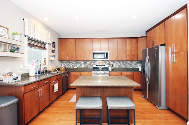 kitchen with appliances with stainless steel finishes, a center island, sink, and light hardwood / wood-style flooring